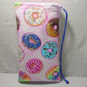 May include: A pink drawstring bag with a donut pattern. The donuts are various colors with sprinkles and chocolate frosting.