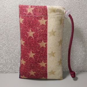 May include: A red and white drawstring bag with a star pattern. The bag is made of fabric and has a red drawstring.