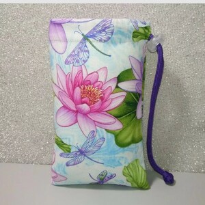 May include: A small, light blue drawstring bag with a floral print featuring pink water lilies and blue dragonflies. The bag has a purple drawstring.