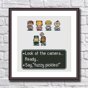 May include: Cross-stitch pattern featuring characters from the video game Earthbound. The characters are standing in a line and the text below reads: "Look at the camera... Ready... Say, "fuzzy pickles!"