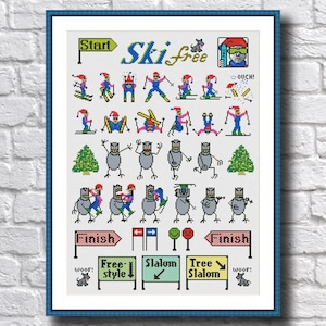 Op de afbeelding: Kruissteekkunstwerk in een blauwe lijst met een skithema. Het ontwerp bevat skiërs, bomen en borden met tekst als "Start", "Ski Free", "Finish", "Freestyle", "Slalom" en "Tree Slalom". Het kleurenpalet is voornamelijk blauw, rood, groen en wit.