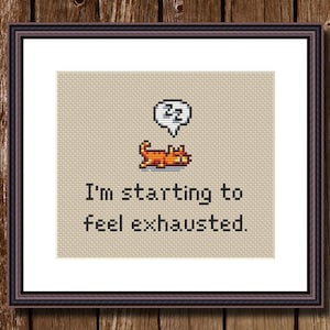 May include: Cross-stitch pattern featuring a pixelated orange cat with a speech bubble above it that says "zz". The text below the cat reads "I'm starting to feel exhausted."