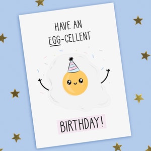 A funny birthday card with a hand drawn image of a fried egg (sunny side up) wearing a party hat with blue and pink stripes. It is throwing confetti. The card caption is: Have An Egg-Cellent Birthday