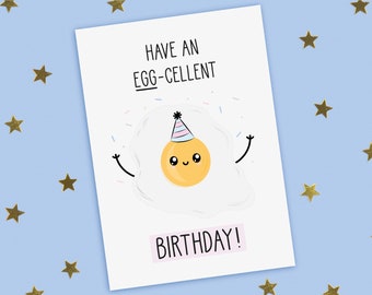 May include: A white card with a cartoon illustration of a fried egg wearing a party hat and confetti. The text on the card reads "Have an Egg-cellent Birthday!"