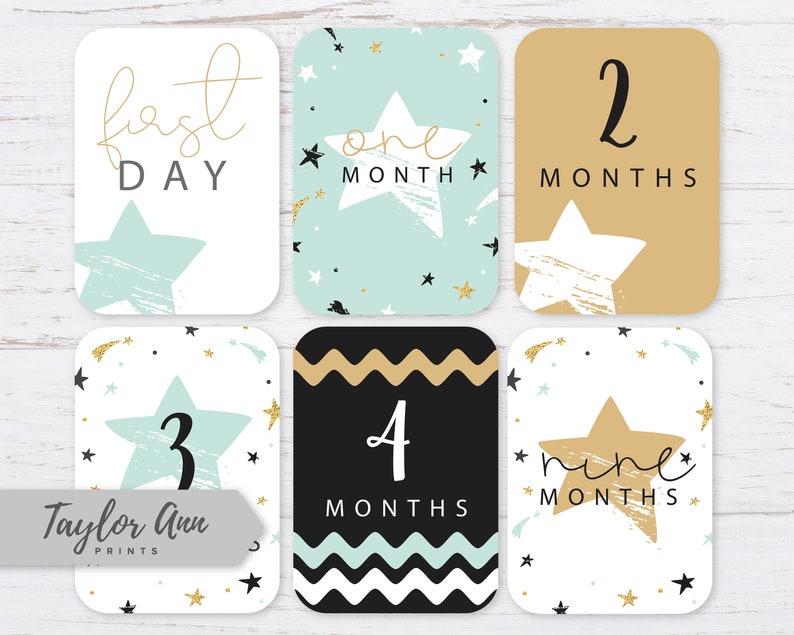 May include: Set of ten baby milestone cards with a star theme. The cards feature a white background with gold and blue stars. The numbers one through nine are featured on the cards, along with the words "first day", "one month", "two months", "three months", "four months", "five months", "six months", "seven months", "eight months", and "nine months".