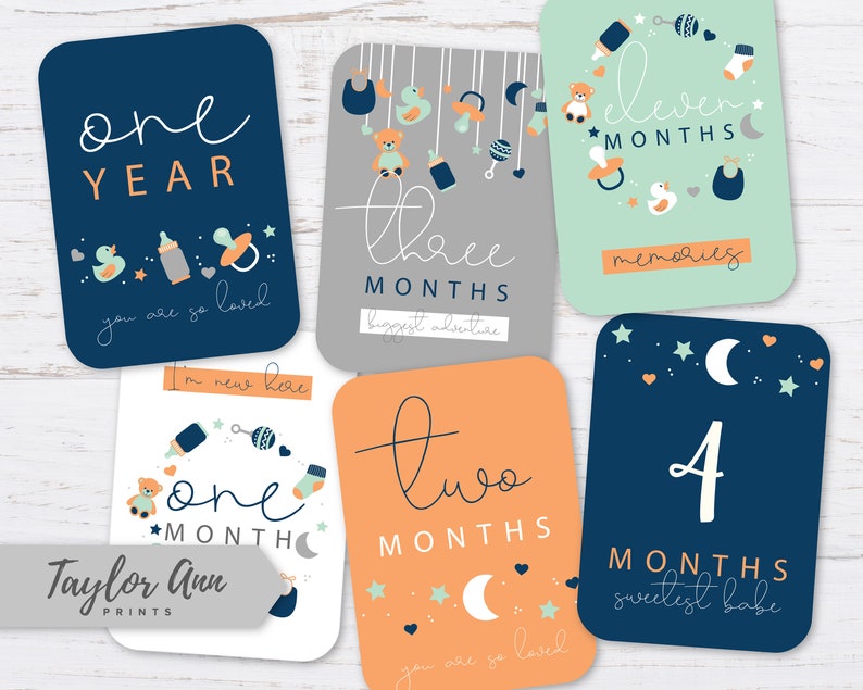 May include: Ten cards with blue, orange, and green backgrounds featuring illustrations of baby items and the text "one year", "three months", "eleven months", "two months", "four months", "one month", "you are so loved", "biggest adventure", "memories", "sweetest babe", and "I'm new here".