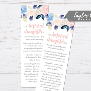 以下が含まれることがあります： ピンクとブルーの花柄のしおりで、「私は天の両親の愛する娘であり、神聖な性質と永遠の運命を持っています。」というテキストが書かれています。しおりには、「Taylor Ann Prints」というテキストも含まれています。