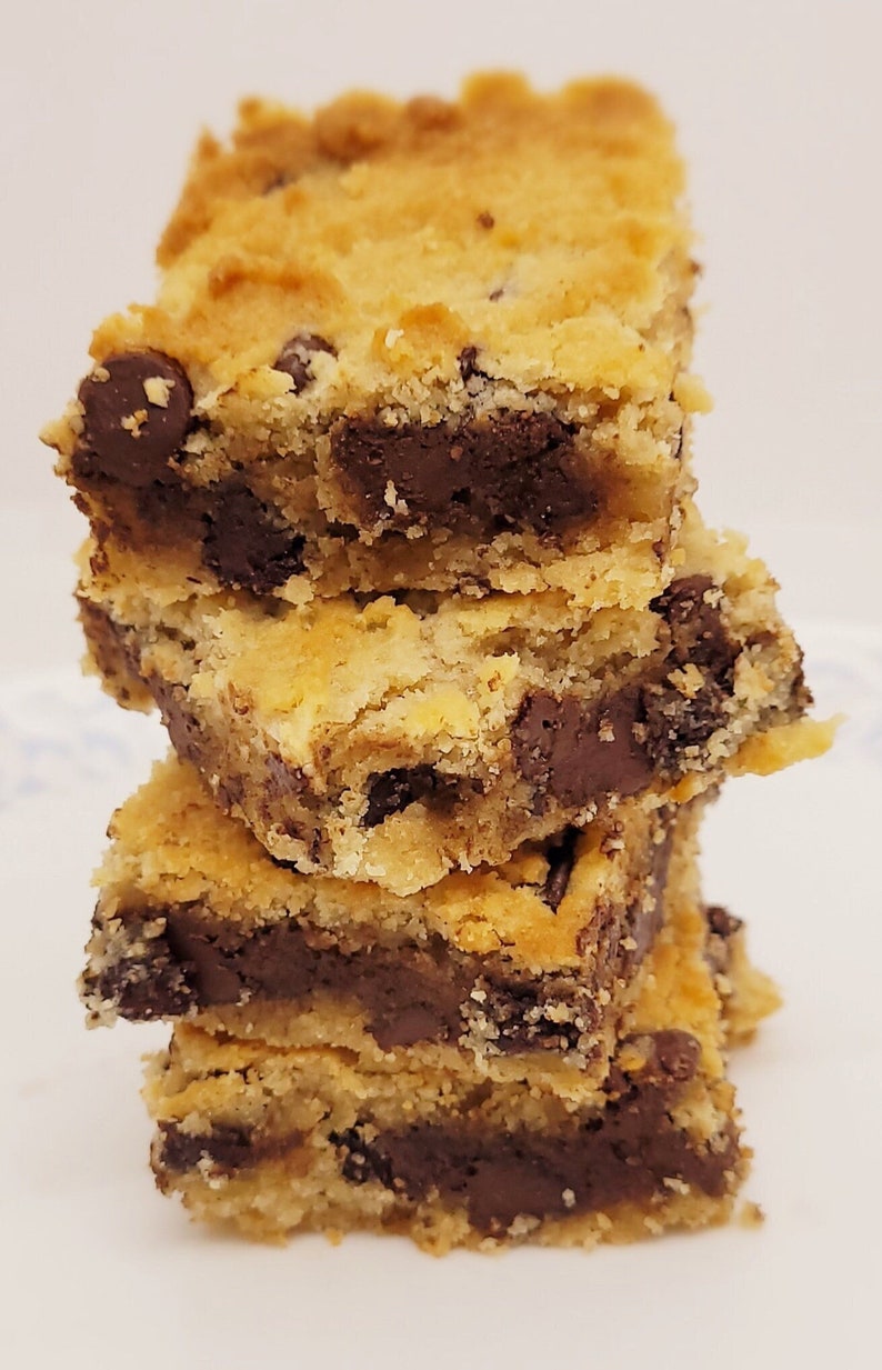 May include: A stack of three golden brown chocolate chip cookie bars with chocolate chips visible throughout the bars.