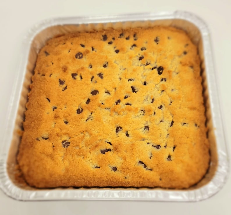 May include: A golden brown cookie bar with chocolate chips in a silver baking pan.
