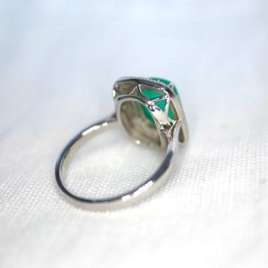 May include: A silver ring with a green gemstone set in a delicate, openwork design.