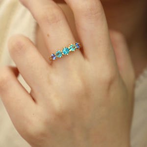 May include: A gold ring with a row of blue and turquoise gemstones.