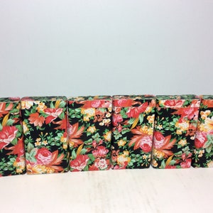 Puede incluir: Seis peque&ntilde;as cajas rectangulares con motivos florales. Las cajas son negras con flores rojas, naranjas, amarillas y verdes.