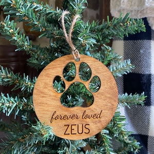 May include: A wooden Christmas ornament with a paw print cutout and the text "forever loved ZEUS".
