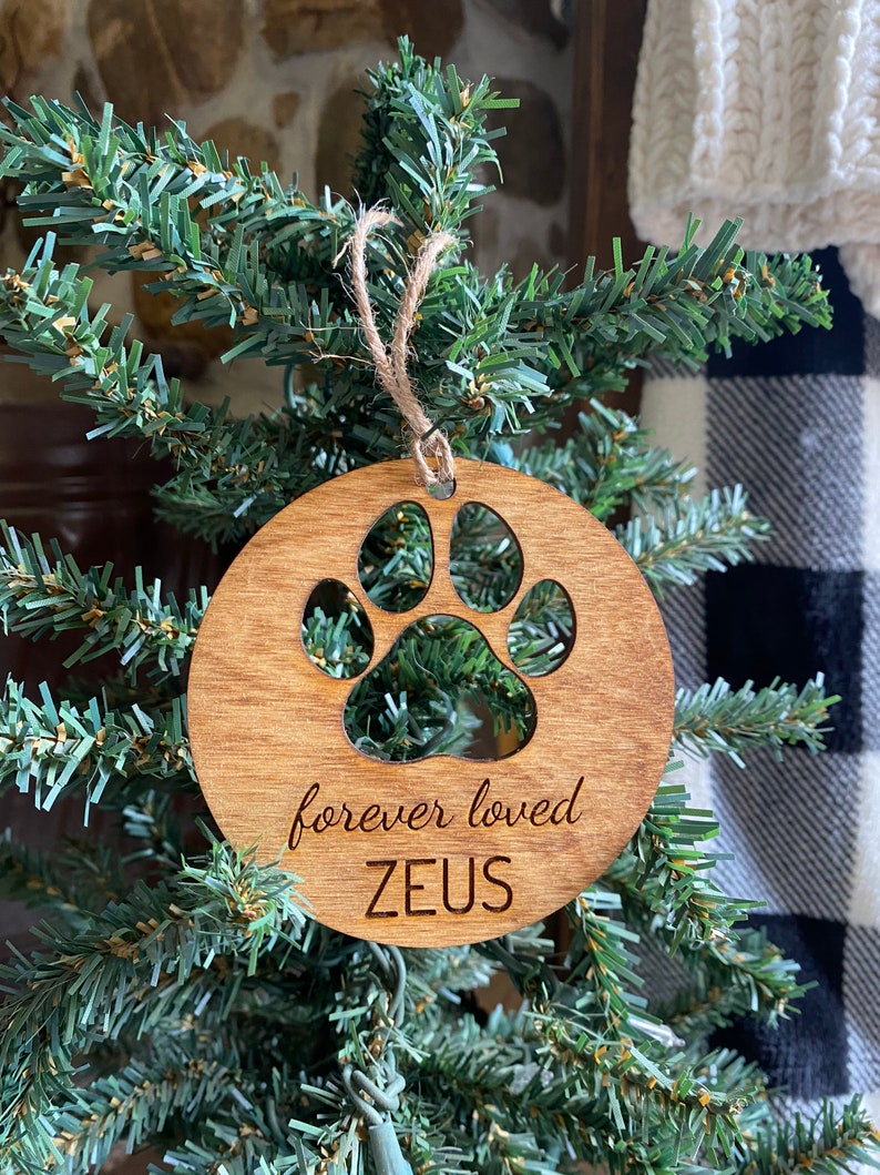 May include: A wooden Christmas ornament with a paw print cutout and the text "forever loved ZEUS".