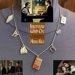 May include: Silver-toned necklace featuring charms related to the movie "Interview with the Vampire." Charms include a coffin, ship, flames, book, cassette tape, theater masks, and vampire teeth. The book charm has the movie title.