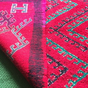 May include: A red and black rug with a geometric pattern. The rug has a fringe border and is folded in half.