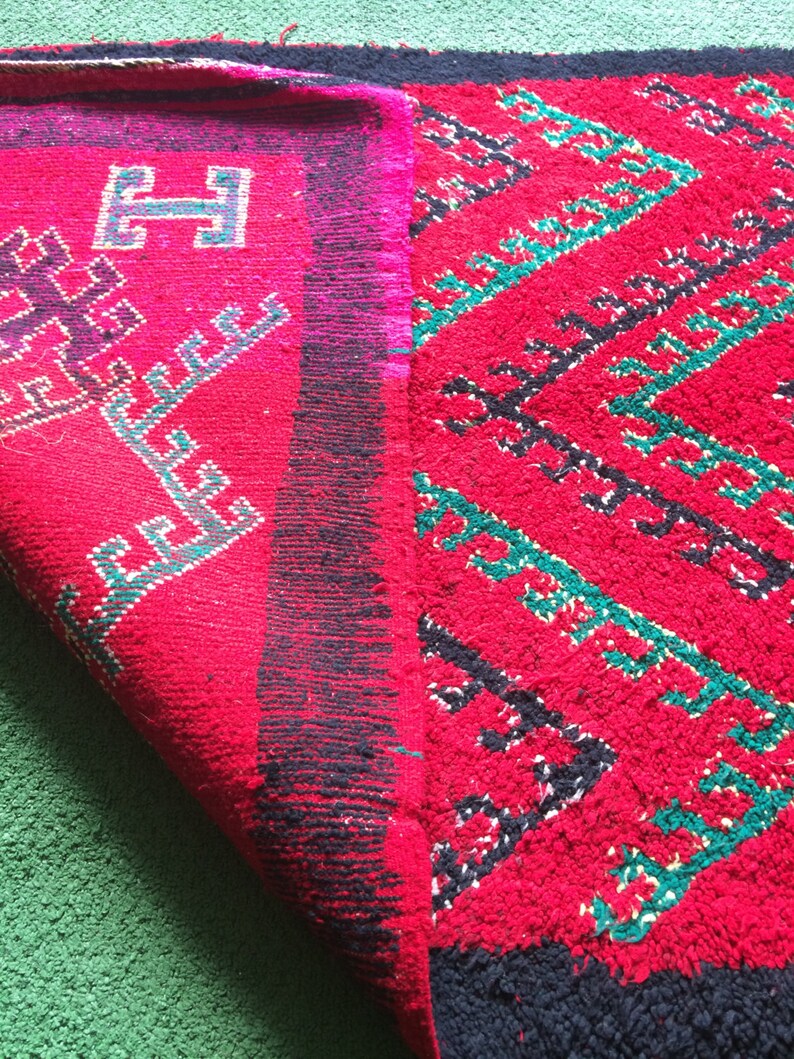 May include: A red and black rug with a geometric pattern. The rug has a fringe border and is folded in half.