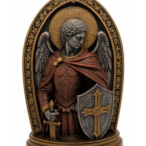 Op de afbeelding: Een decoratief harsbeeld van een engel in harnas, met een textuur in rood en goud. De figuur houdt een zwaard en een schild met een kruisembleem vast, geplaatst voor een boogvormig, gedetailleerd goudkleurig frame met een cirkelvormige halo.