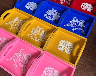 May include: Nine wooden serving trays with handles, each painted in a different color and featuring a white design. The designs include birds, elephants, and floral patterns.