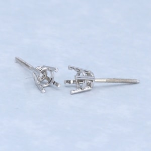 May include: Two silver earring settings with prongs for holding a gemstone. The settings are designed to be attached to a post.