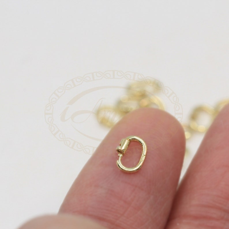 K&ouml;nnte beinhalten: Goldfarbener Metall-Hummerverschluss, eine Art von Schmuckzubeh&ouml;r, das zum Verbinden von Ketten oder Schn&uuml;ren verwendet wird.