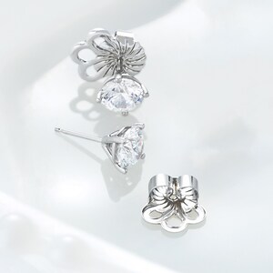 May include: A pair of silver stud earrings with a clear round stone. The earrings have a butterfly-shaped back.