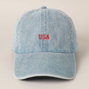 May include: A light blue denim baseball cap with a red embroidered "USA" on the front.