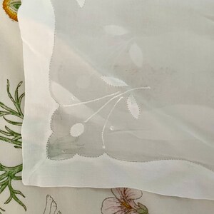 Pode incluir: Toalha de mesa branca transparente com delicados desenhos florais bordados. A toalha de mesa tem uma borda festoneada e &eacute; feita de um tecido leve.