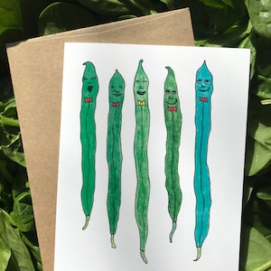 May include: A greeting card with a whimsical illustration of five green beans with faces and bow ties. The beans are drawn in a cartoon style with different shades of green and blue.