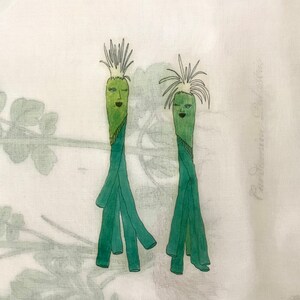 Pode incluir: Duas figuras de desenho animado verdes com rostos e cabelos, desenhadas em um fundo de tecido branco.