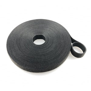 May include: A roll of black hook and loop fastener tape. The tape is rolled up and a small section is unrolled to show the texture of the material.