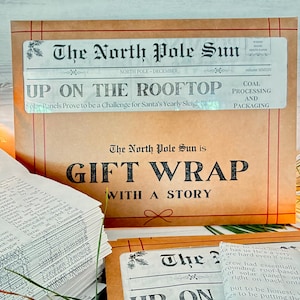 May include: A tan paper gift wrap sheet featuring a newspaper-style header titled The North Pole Sun, with the headline Up On The Rooftop and the text Gift Wrap With A Story. The design includes red line borders and a small red bow illustration.