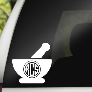 May include: White vinyl decal of a mortar and pestle with a monogram of the letters ACS inside a circle.