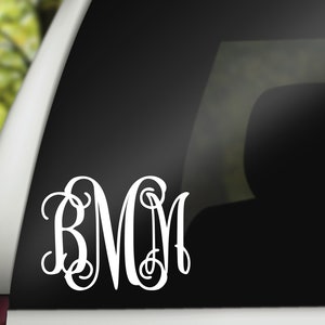 May include: A white vinyl decal with the monogram "B.M.C." in a cursive font. The decal is applied to the rear window of a car.