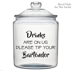 May include: A clear glass jar with a black decal that reads "Drinks are on us please tip your Bartender".
