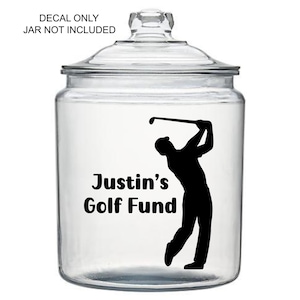 May include: A clear glass jar with a lid, featuring a black silhouette of a golfer mid-swing. The text "Justin's Golf Fund" is printed in black. The text "DECAL ONLY JAR NOT INCLUDED" is also present.