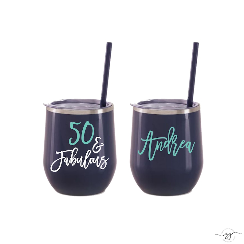 May include: Two stainless steel tumblers with lids and straws. One tumbler is navy blue with white text that says "50 & Fabulous" in teal. The other tumbler is navy blue with the name "Andrea" in teal.