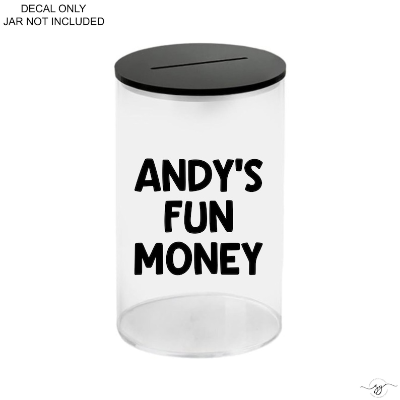 Op de afbeelding: Een doorzichtige cilindervormige houder met een zwarte deksel voorzien van een horizontale gleuf. De voorzijde toont de zwarte tekst ANDY'S FUN MONEY. Links bovenaan staat DECAL ONLY JAR NOT INCLUDED.