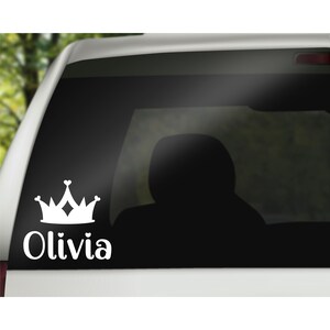 May include: White vinyl car decal with a crown and the name Olivia. The crown has a heart shape at the top and bottom.