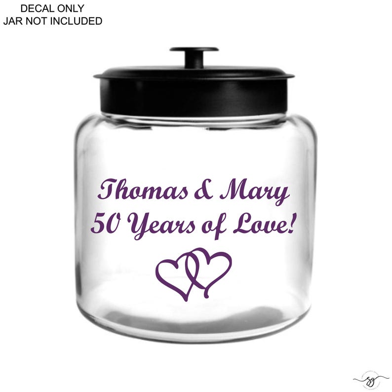 Op de afbeelding: Een doorzichtige glazen pot met een zwarte deksel en een paarse sticker met de tekst Thomas & Mary 50 Years of Love! en twee in elkaar grijpende harten. De afbeelding bevat de tekst DECAL ONLY JAR NOT INCLUDED.