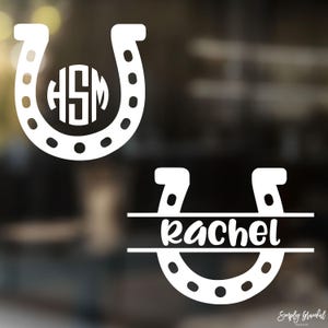 May include: Two white horseshoe decals. One features the initials "HSM" inside. The other has the name "Rachel" in cursive script. The decals are designed for personalization and are likely for a car or home decor.