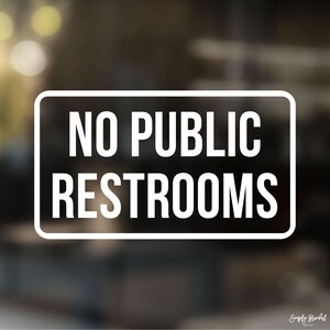 May include: White sign with black text that reads "NO PUBLIC RESTROOMS" on a blurred background.