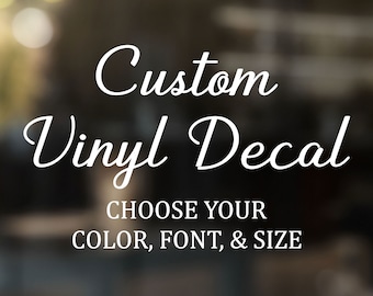 May include: A white vinyl decal featuring the text Custom Vinyl Decal in a cursive script font, followed by the text CHOOSE YOUR COLOR, FONT, & SIZE in a bold, sans-serif typeface. The lettering is displayed against a dark, blurred background.