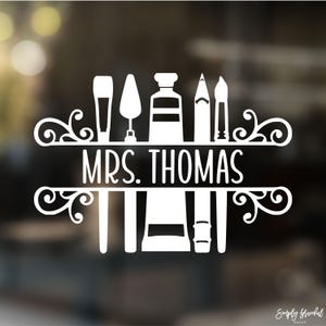 May include: White vinyl decal with the text "MRS. THOMAS" in a decorative font. The decal features a paintbrush, palette knife, paint tube, pencil, and paintbrush. The decal is perfect for a teacher's door or classroom.