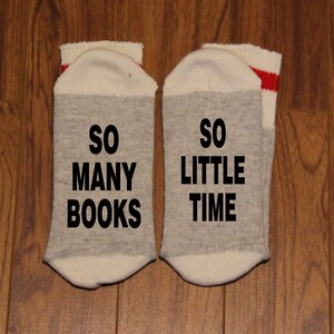 May include: A pair of grey and white socks with red stripes. The socks have the text "So many books" and "So little time" printed on them.