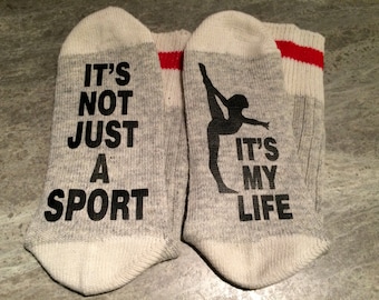 May include: A pair of grey and white socks with red stripes. One sock has the text "It's not just a sport" and the other sock has the text "It's my life" and a silhouette of a gymnast.