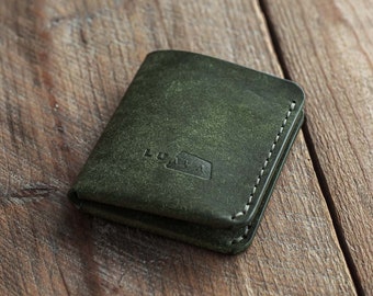 Puede incluir: Una cartera de cuero verde oscuro con un borde cosido y la palabra "LUMIA" grabada en la parte delantera.