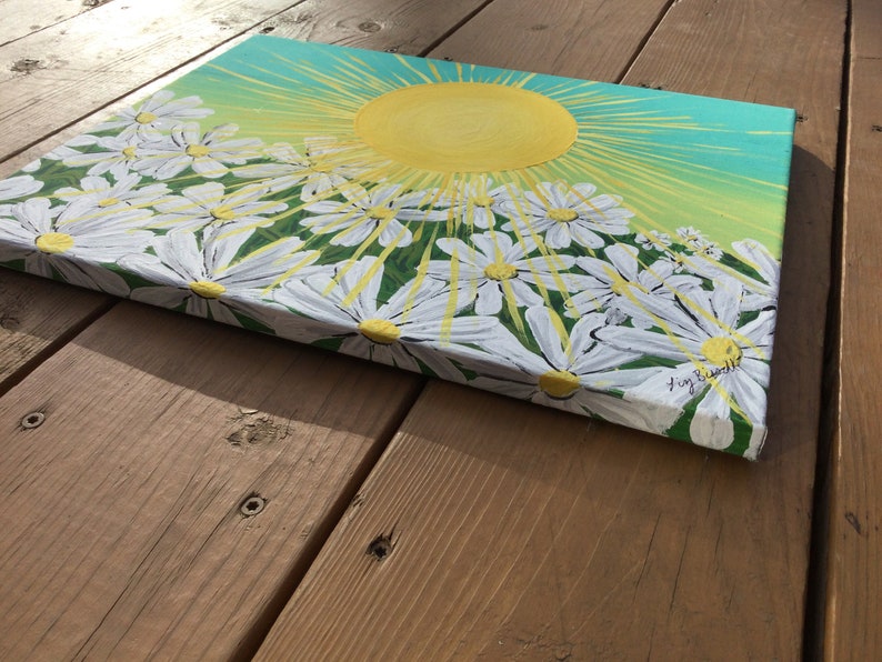 May include: A painting of a bright yellow sun with rays shining down on a field of white daisies. The background is a gradient of green and blue.