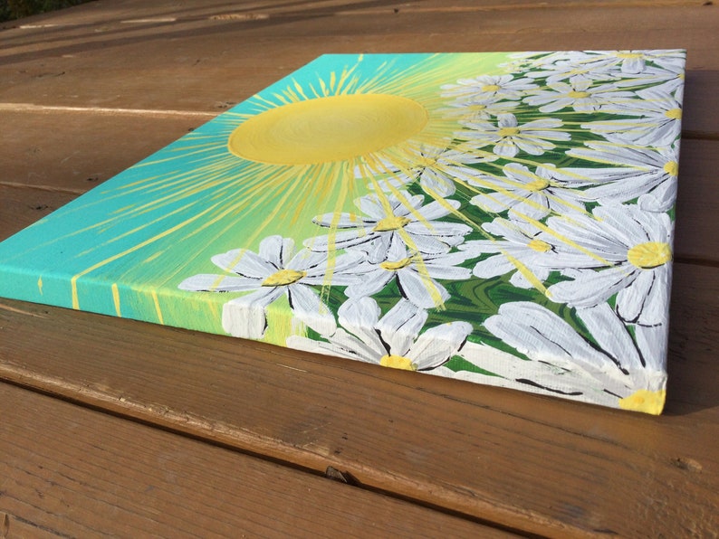 May include: A painting of a bright yellow sun with rays of light shining down on a field of white daisies with yellow centers. The background is a gradient of teal and green.
