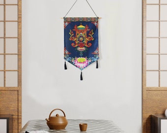 Könnte beinhalten: Ein blauer und goldener Wandteppich mit einem floralen Muster und Quasten, die von unten hängen. Der Wandteppich hängt an einer weißen Wand in einem Raum mit Holzboden und einem Tisch mit einer Teekanne und einer Tasse darauf.